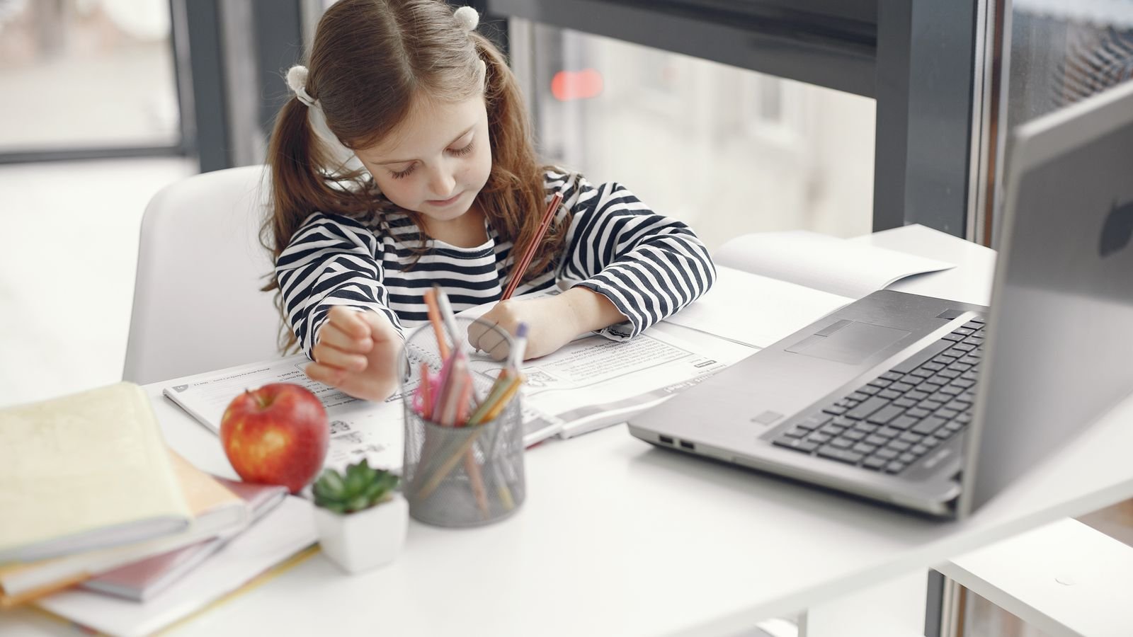 Child at home choosing between a chessboard and a laptop before a live 1 on 1 online class