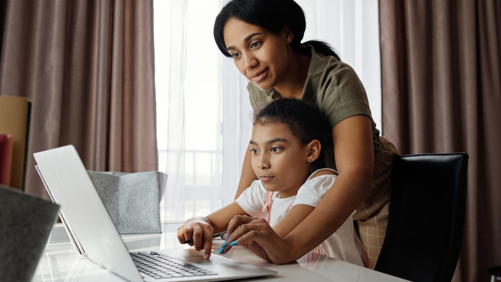 Parent supporting a child at a laptop during a live online 1 on 1 class instead of solving the problem for them