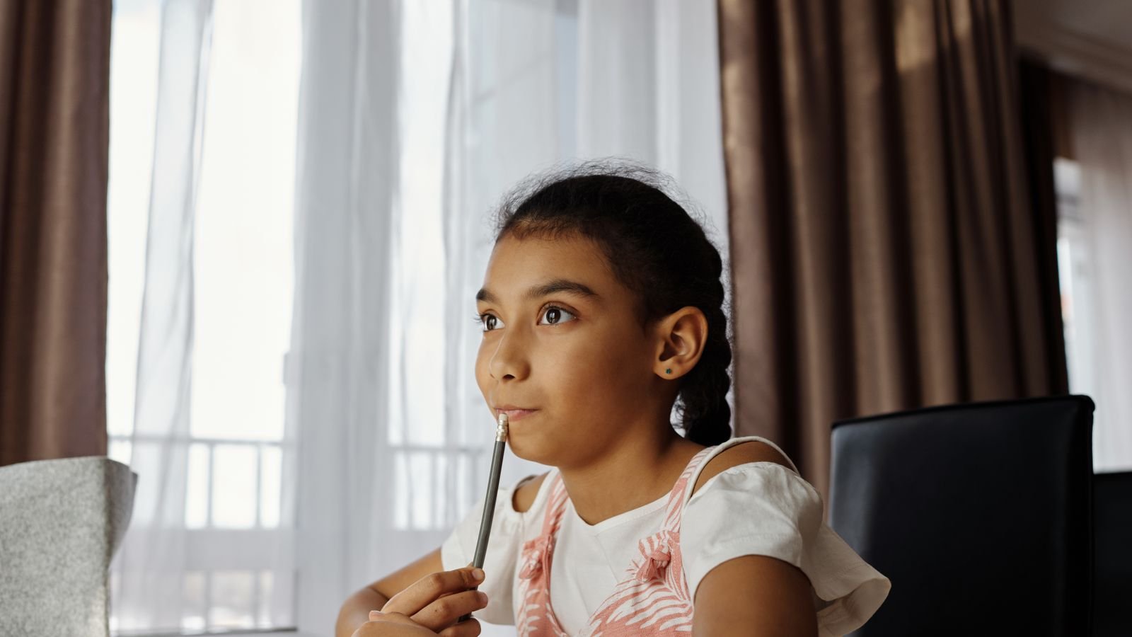 Child thinking hard over a puzzle at a desk, illustrating the left brain vs right brain question in children