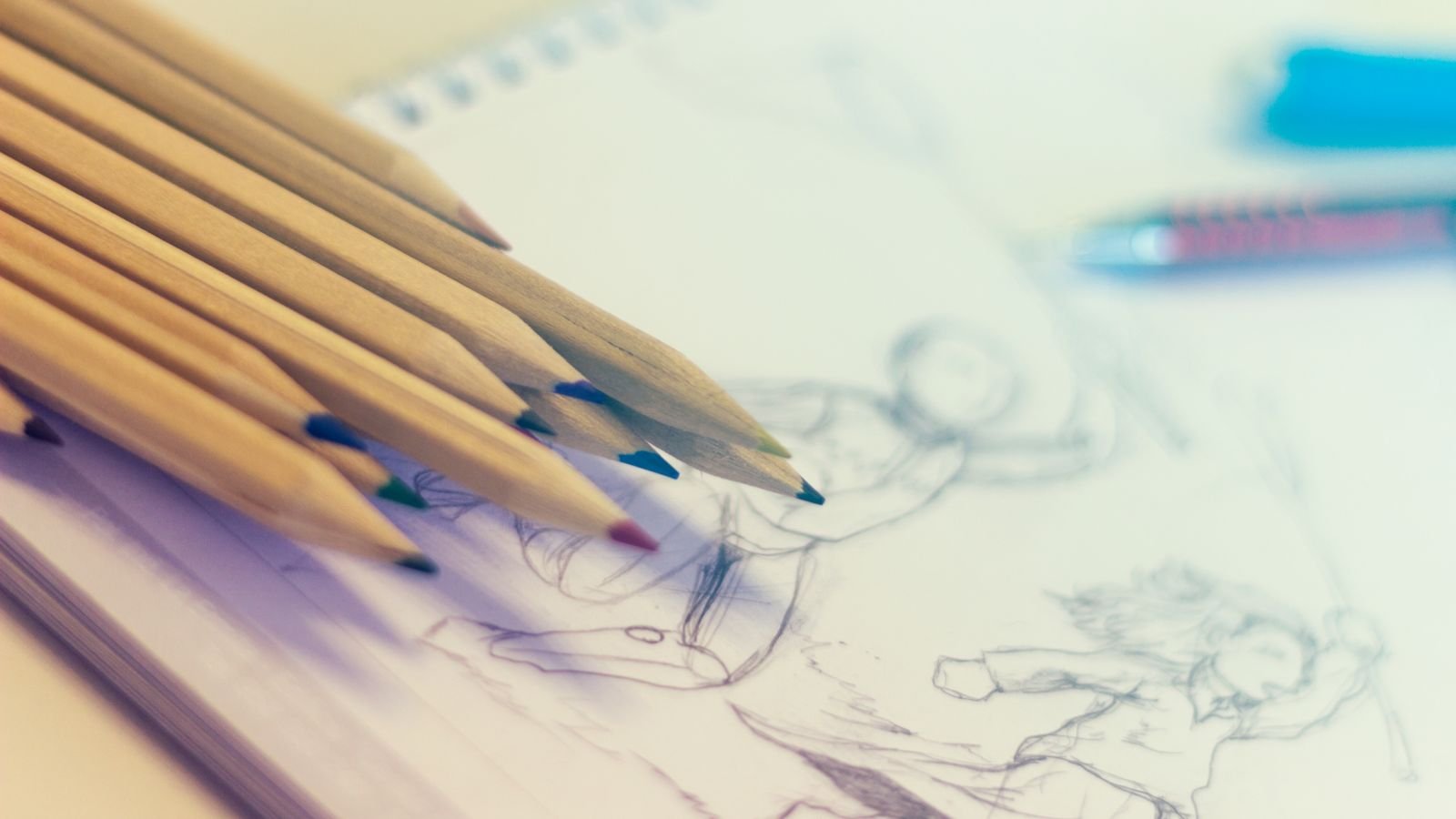 A child's desk with a maths workbook beside a sketchbook and coloured pencils, showing that creative and analytical work belong together