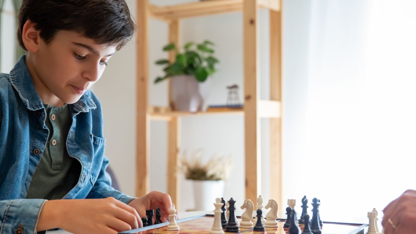 Child in Singapore taking an online chess class on a laptop at home