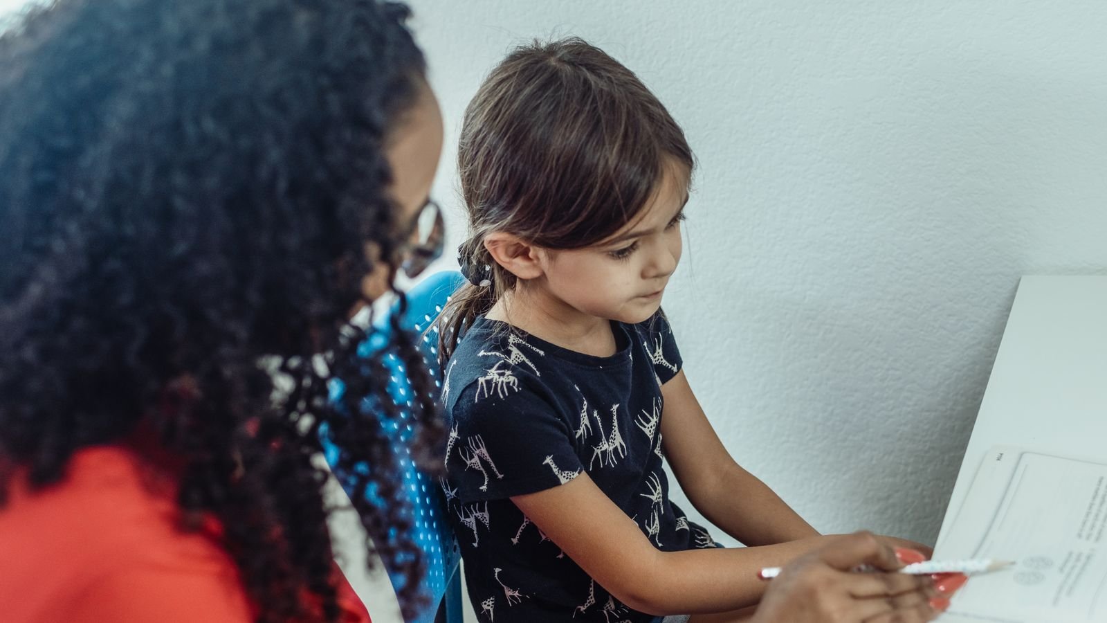 Tutor giving a child full attention during a 1 on 1 maths class at a desk