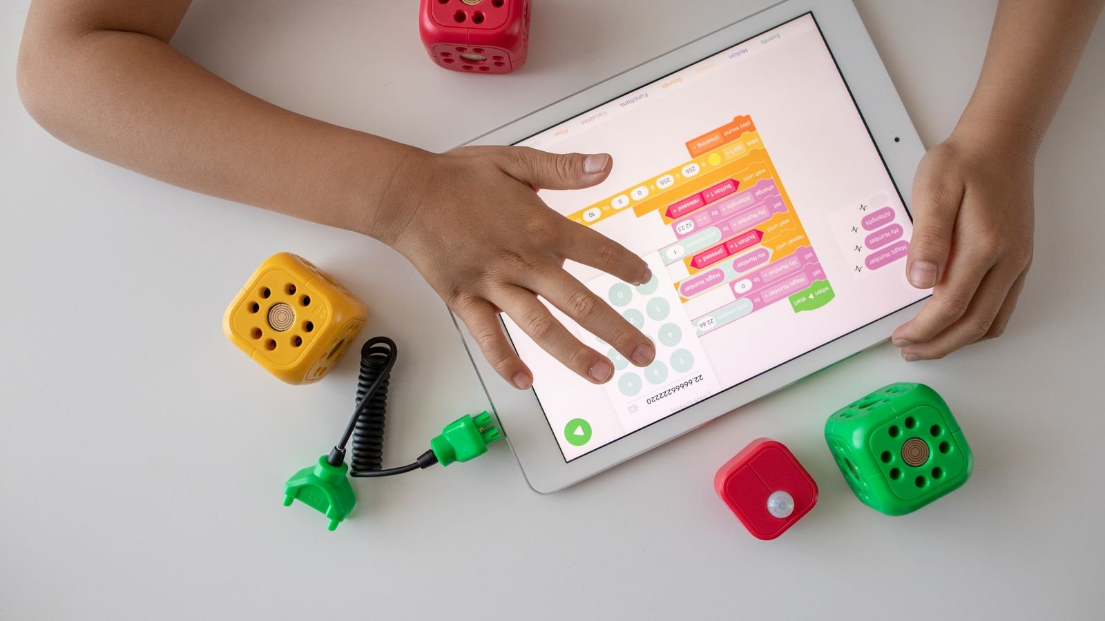 Five year old child using block coding for kids on a tablet with colourful coding blocks