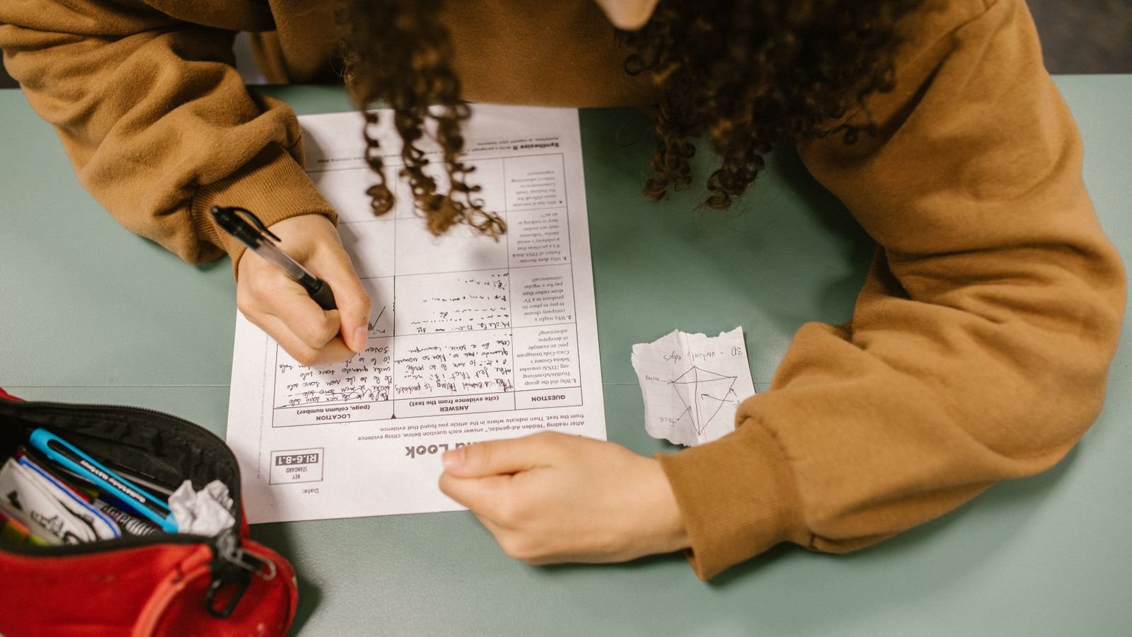 Child aged 9 sitting at a desk looking stuck during a maths test, showing why a child can be good at maths but still fail tests