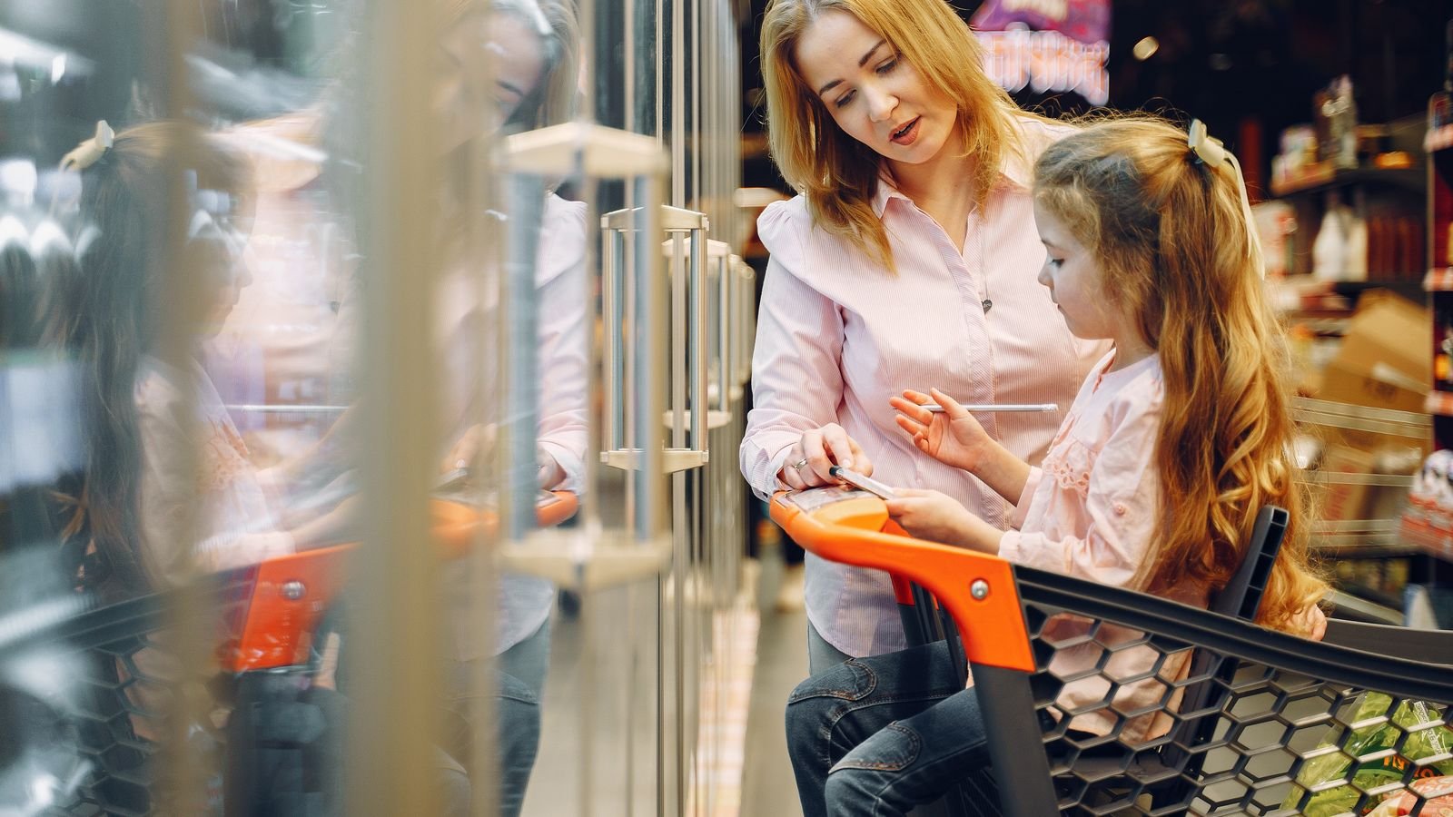 Parent and child comparing prices in a supermarket as everyday maths practice