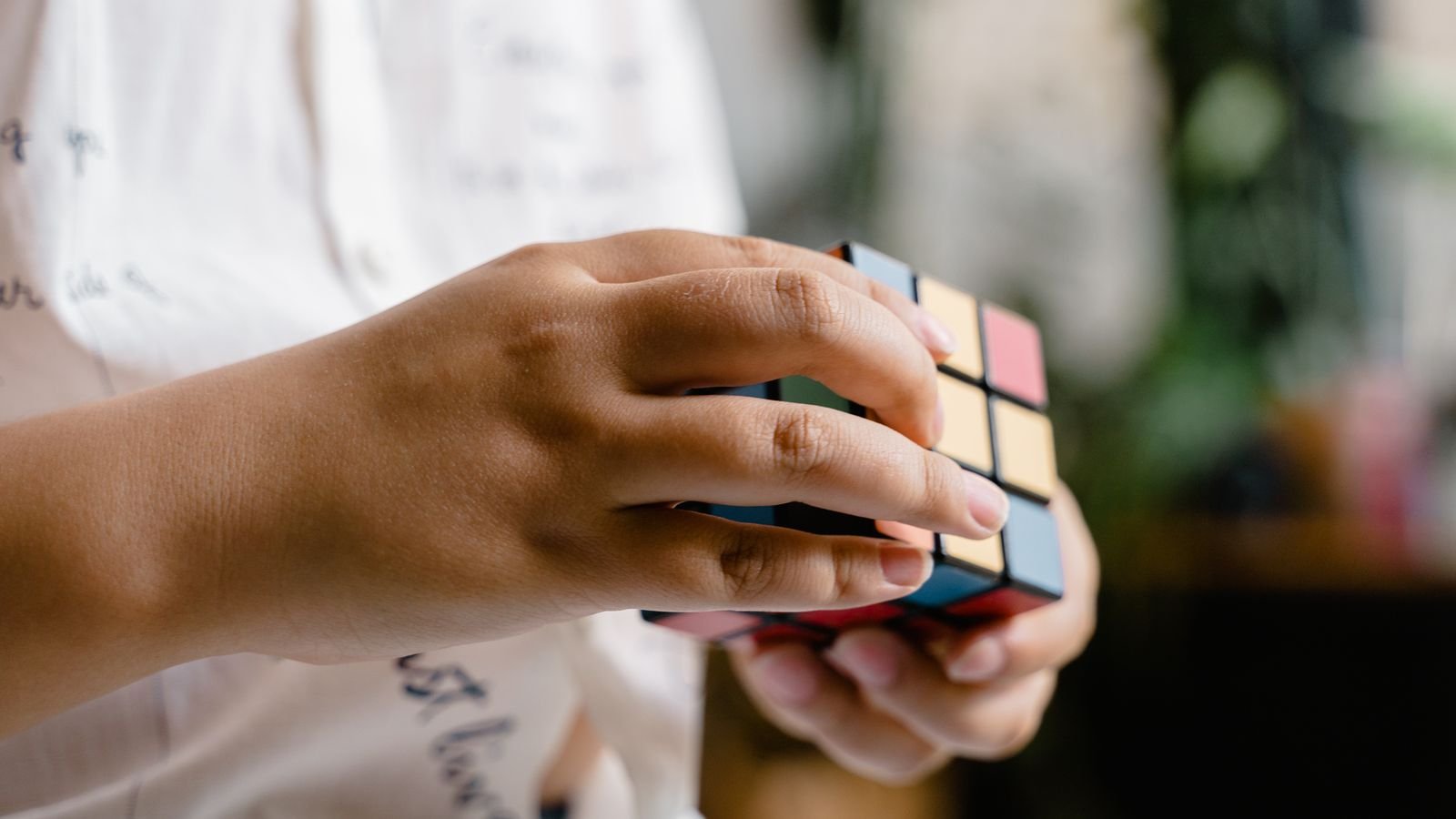 Child solving a Rubik's cube with both hands, building spatial reasoning skills