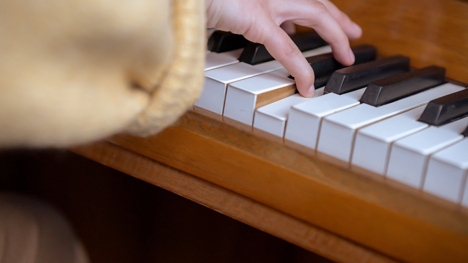 Close up of a child's hands learning finger placement on piano keys in a music lesson