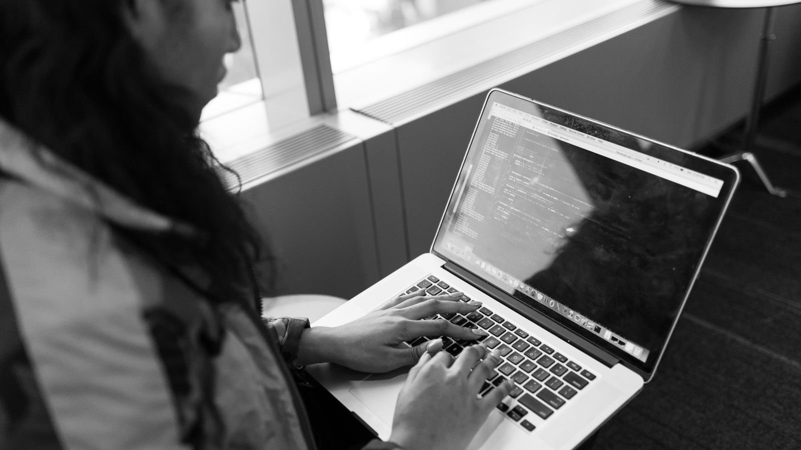 Older child typing Python code on a laptop during an online coding lesson
