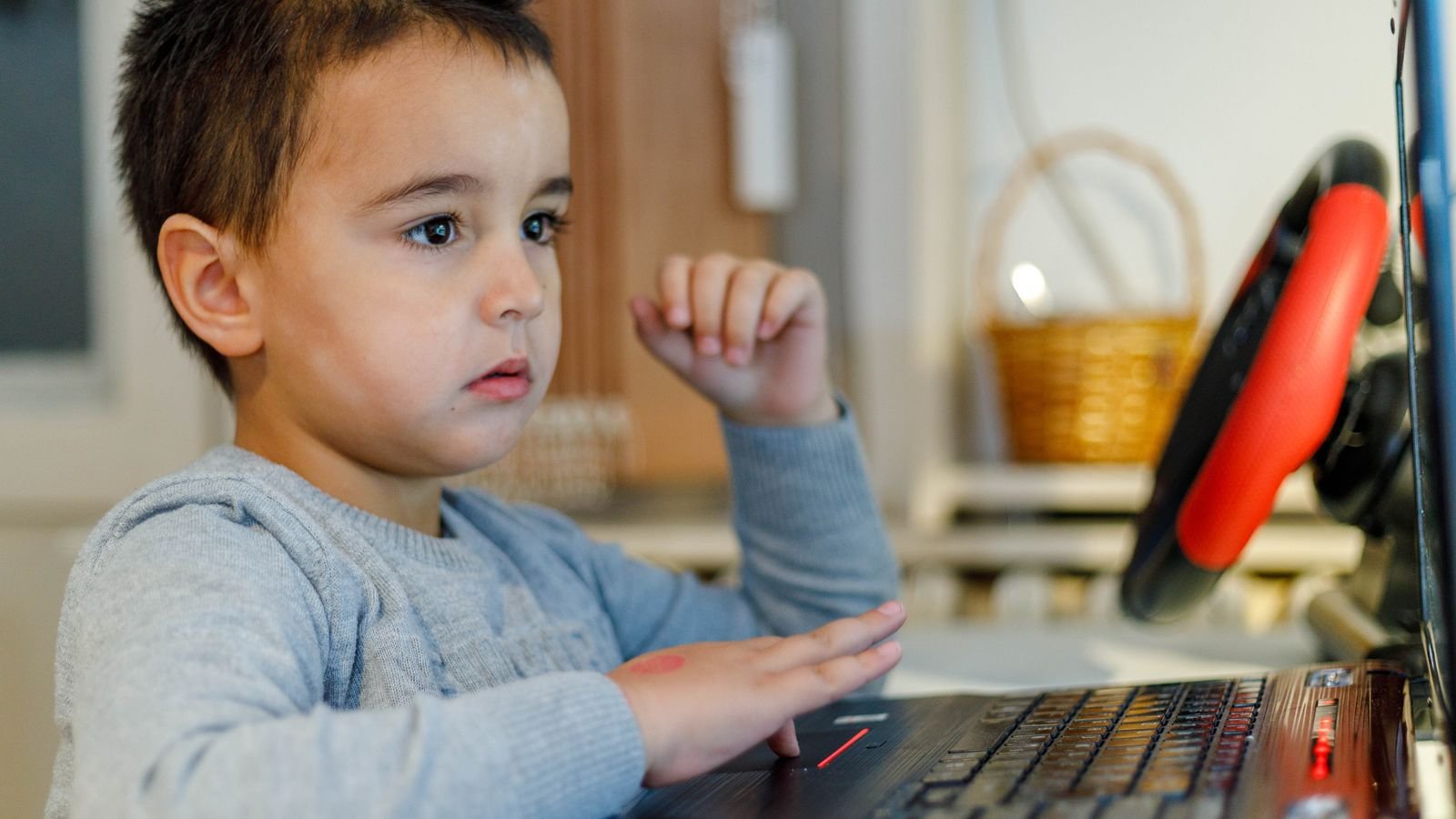 Child building a beginner coding project on a laptop at the kitchen table