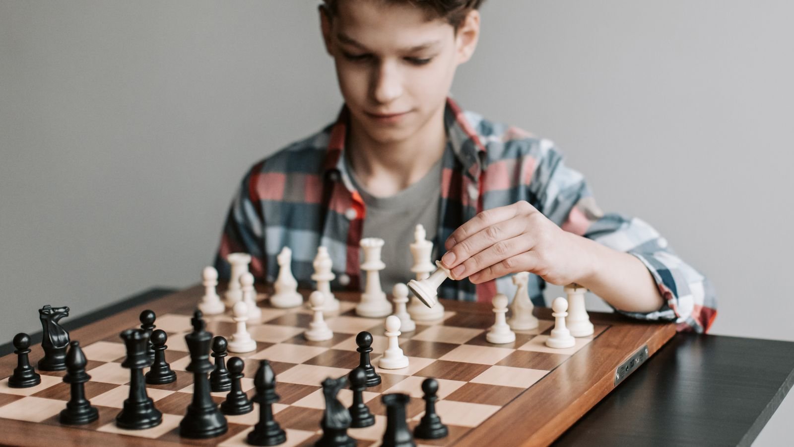 Boy concentrating on his next move while playing chess, showing how chess for kids with ADHD builds focus