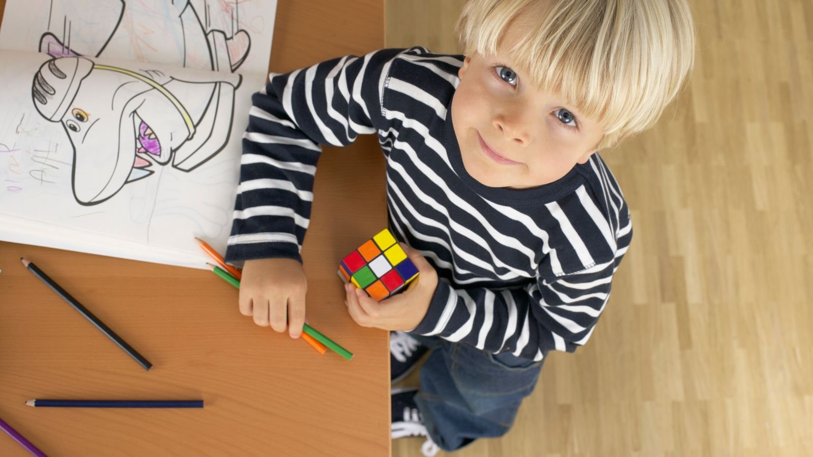 Child holding a Rubik's cube and learning to solve it layer by layer