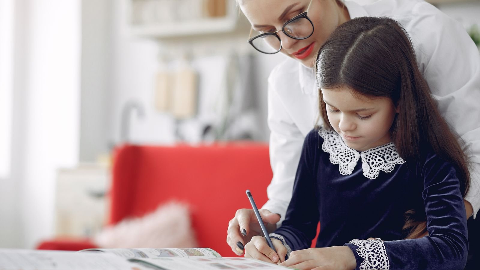 Parent sitting with a child at home working calmly through PSLE revision together