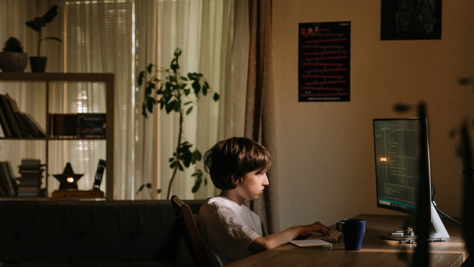 Young child concentrating while learning to code on a laptop at home