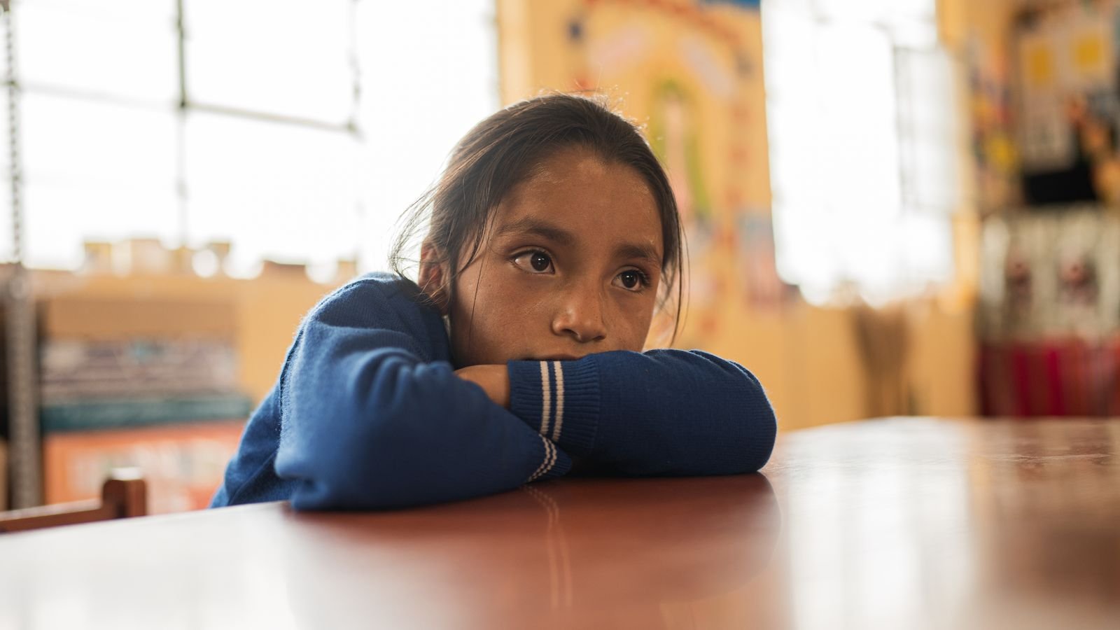 Quiet, shy child in class sitting thoughtfully at a desk during a lesson