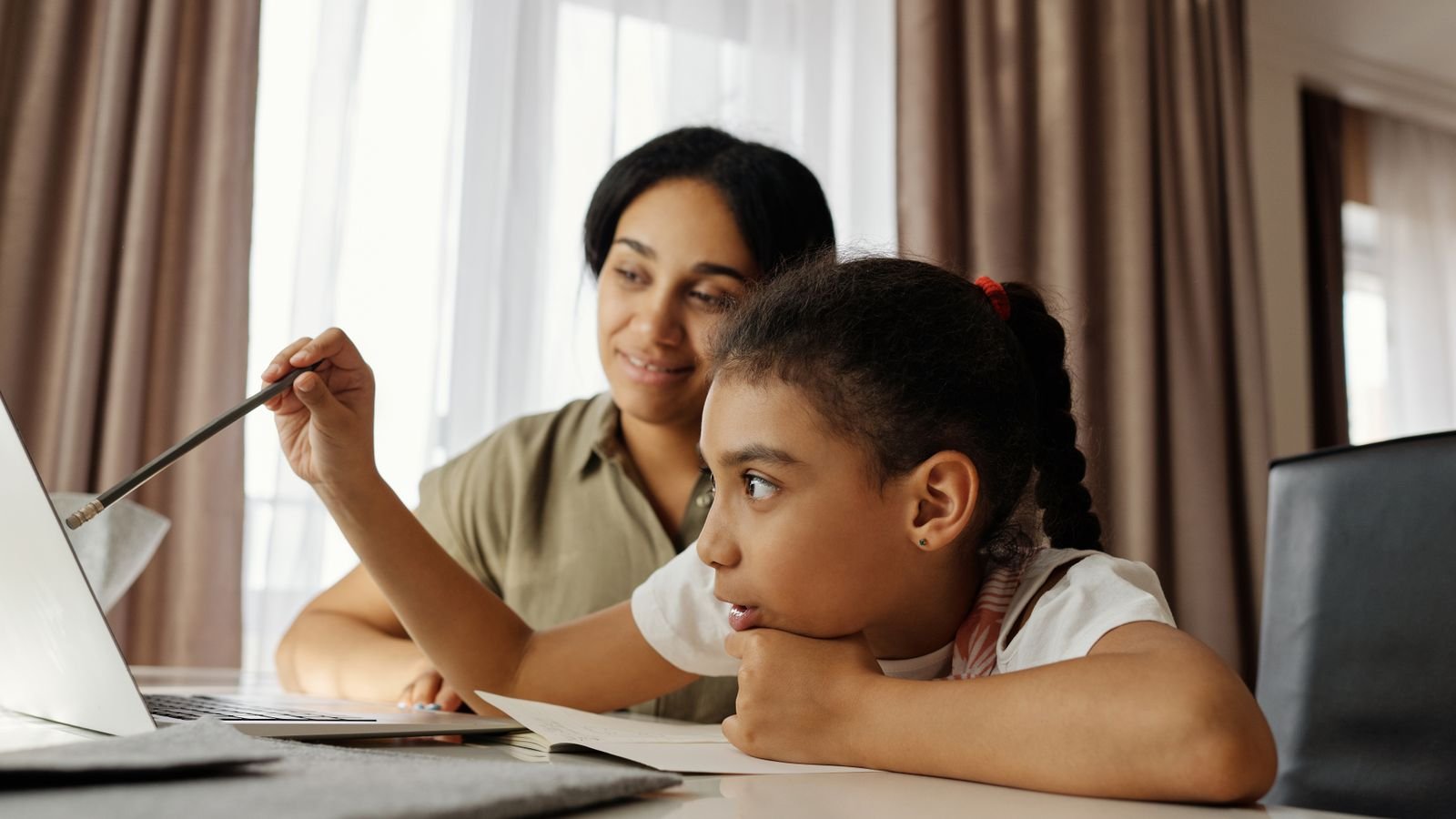 Child smiling and pointing at an online chessboard during a lesson